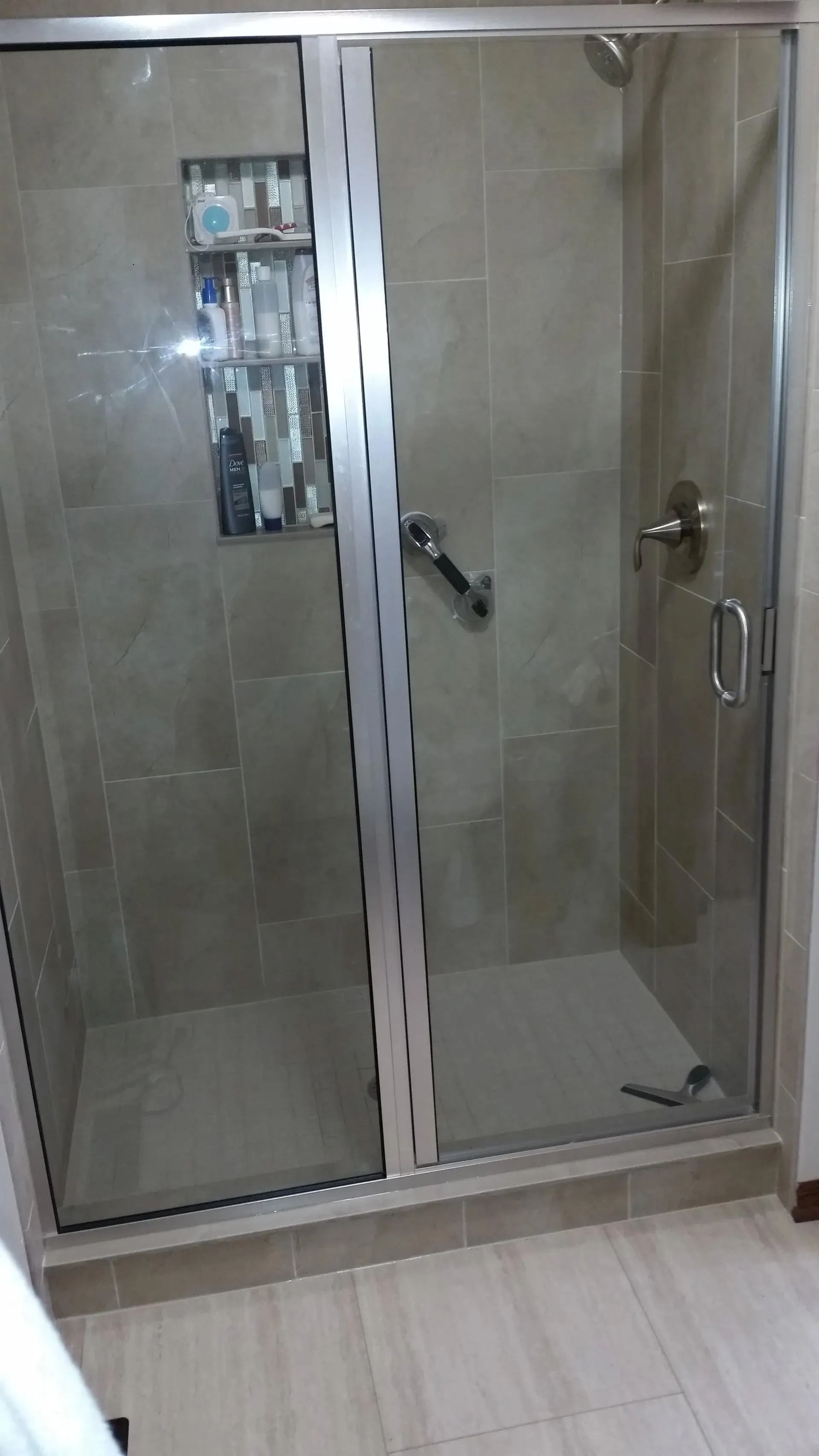 Glass shower enclosure with beige tile walls and sliding doors