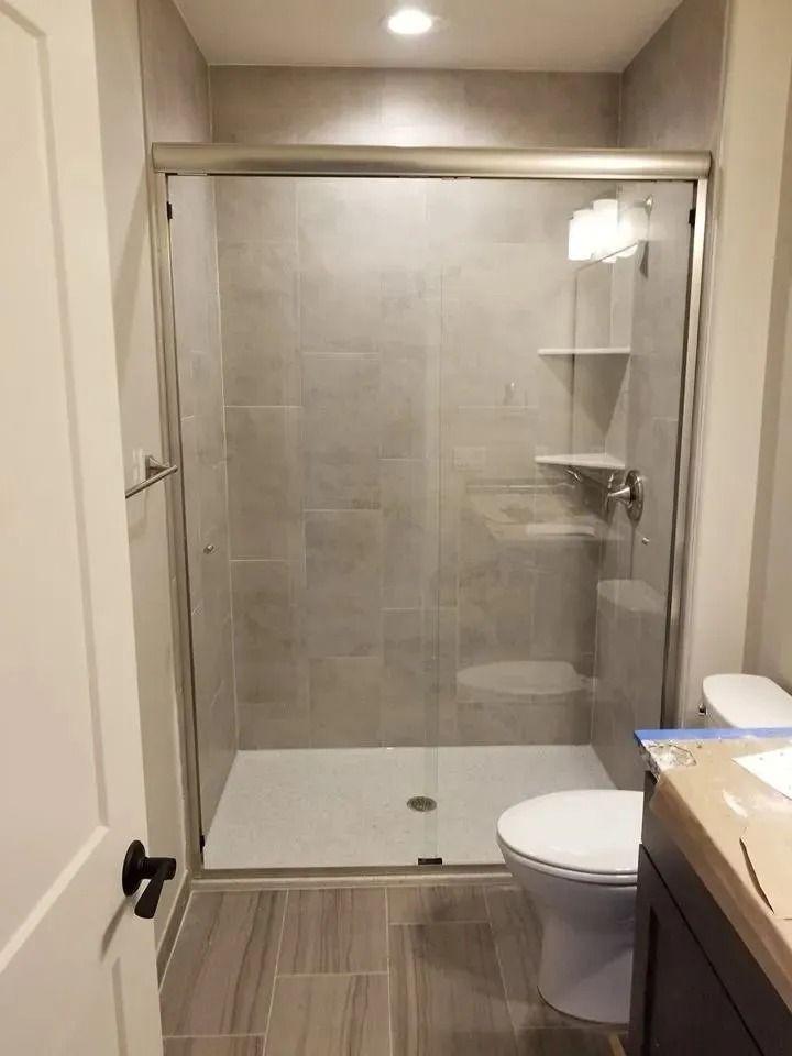 Small bathroom with a tiled walk-in shower, toilet, and vanity sink.