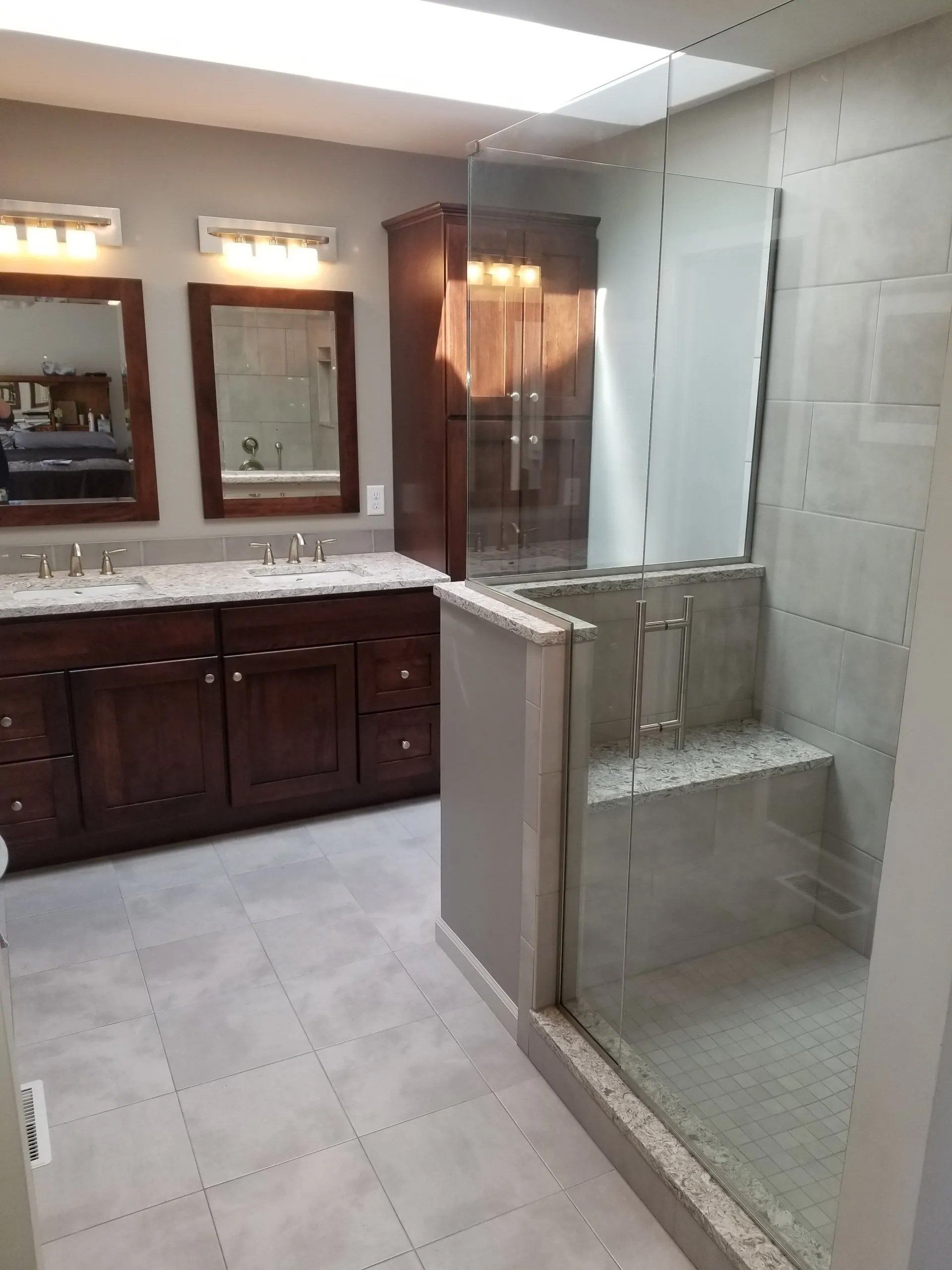 Bathroom with dark wood vanity, mirror, and a glass-enclosed shower stall.