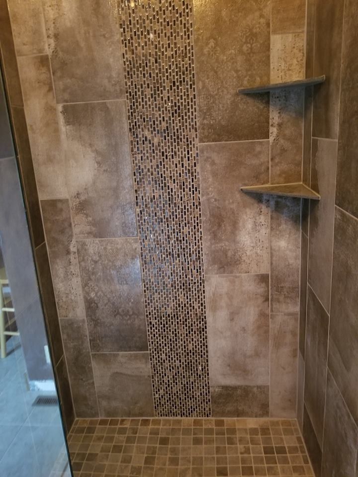 Tiled walk-in shower with mosaic accent strip and two corner shelves