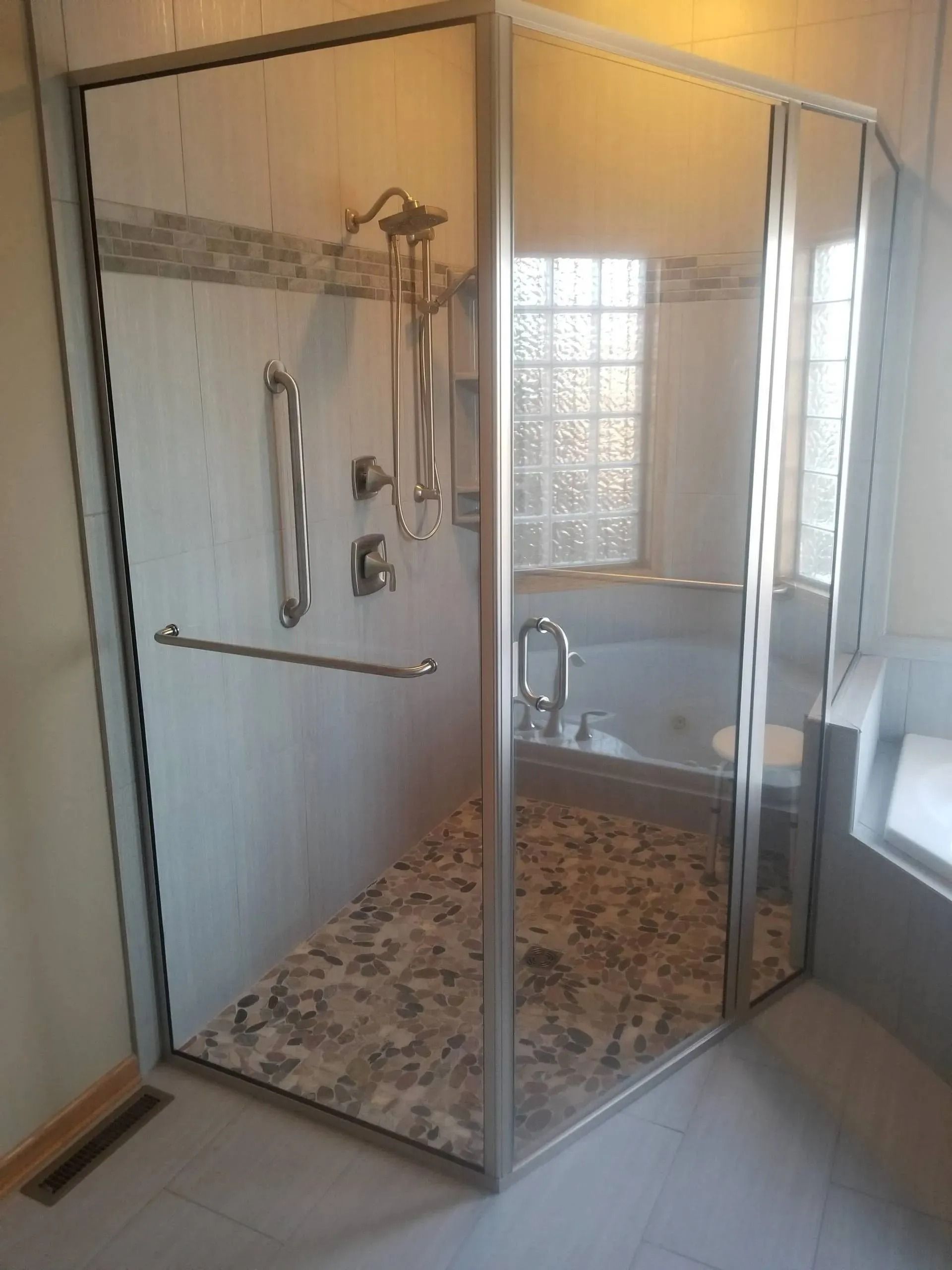 Glass walk-in shower with beige tile, chrome fixtures, and a small window.