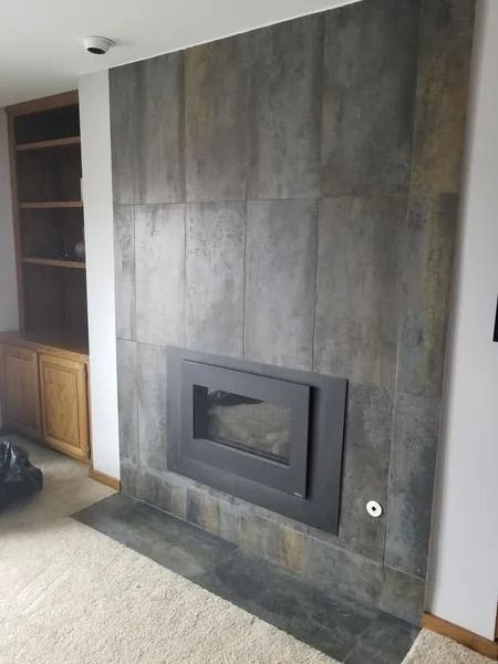 Modern gray fireplace with built-in shelves and wood cabinets in a living room