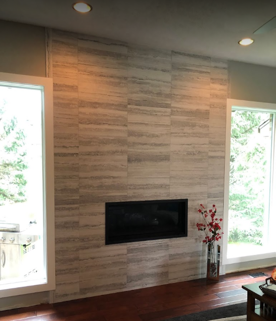 Modern living room with wall-mounted fireplace, wood accent wall, and tall windows on both sides