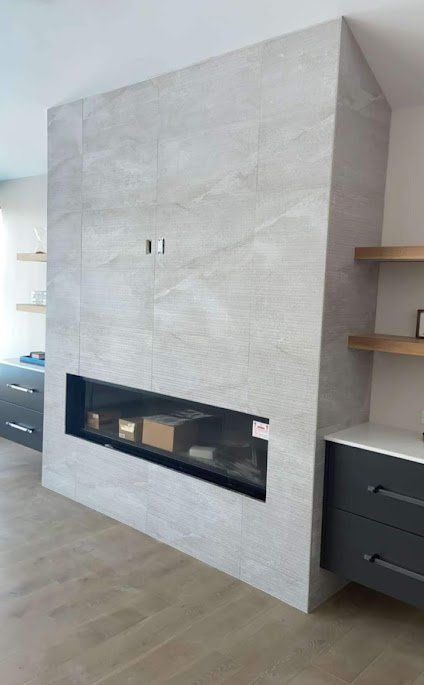Modern light-gray tiled fireplace wall with a long black firebox in a contemporary living room