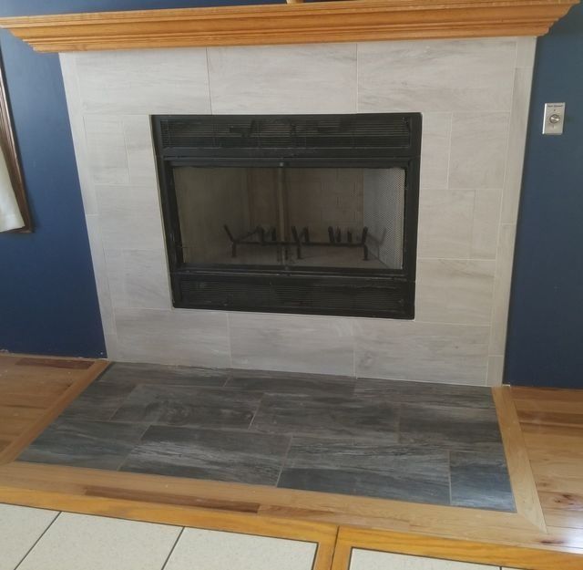 Living room fireplace with black surround, gray tile hearth, and wood mantel against blue and white walls