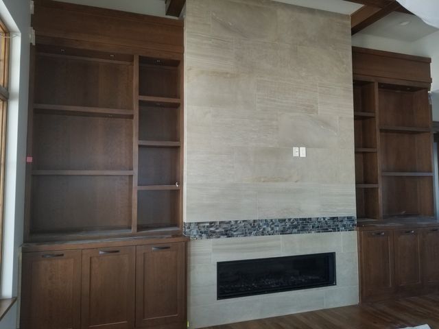 Built-in wooden shelves flanking a stone fireplace in a living room
