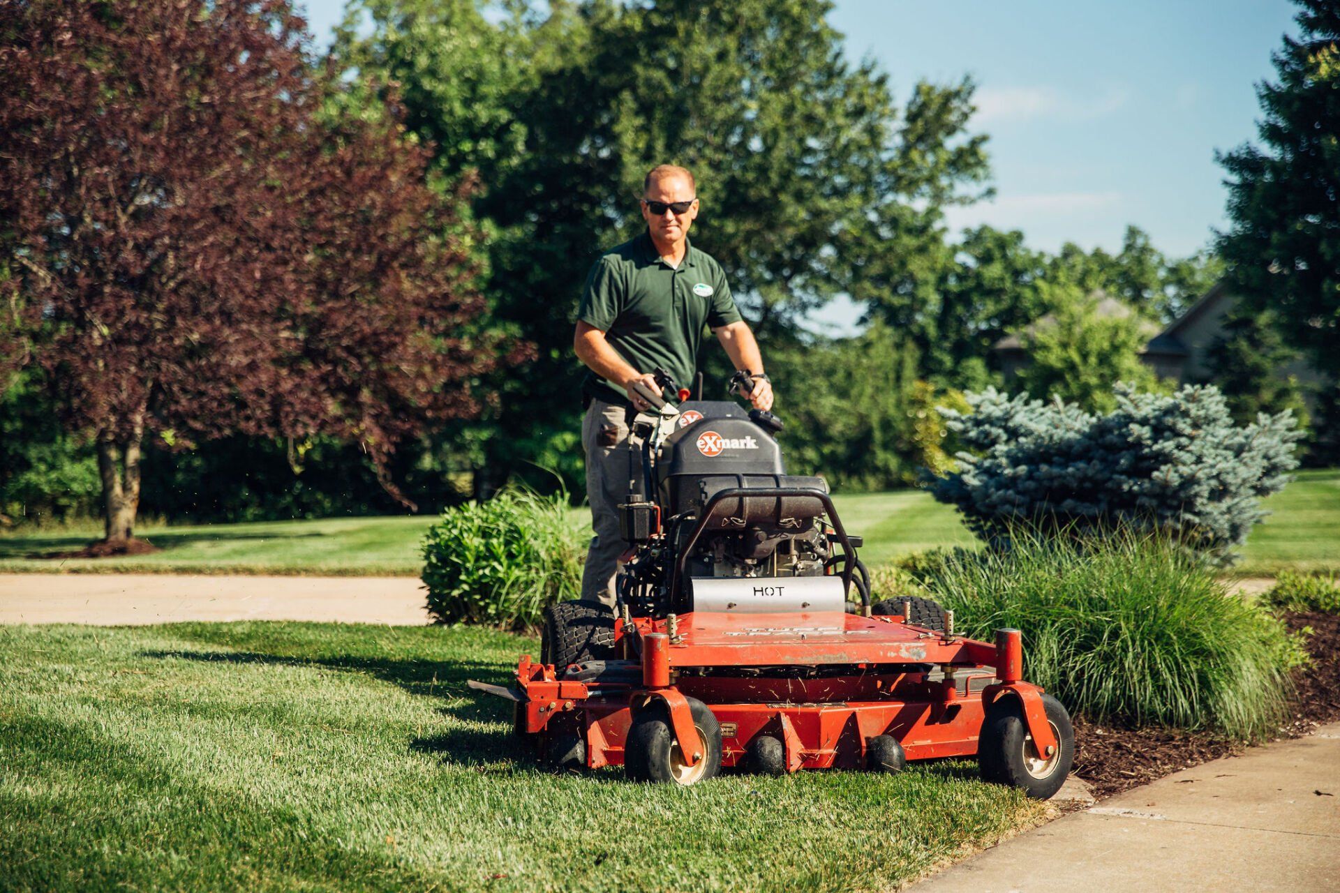 A lawncare professional from Atkins Inc. rides a standing lawn mower and creates a beautiful yard for the clients.