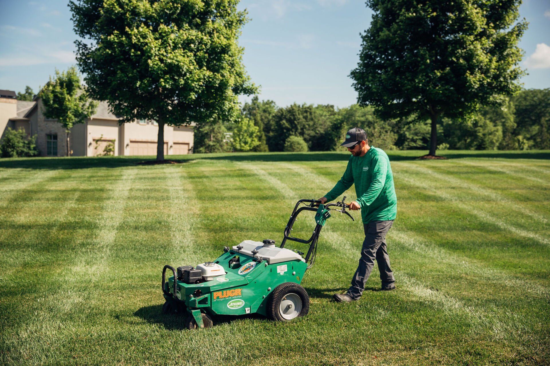 A member of the Atkins Inc. lawncare team uses a motorized aerator to care for a customer's lawn.
