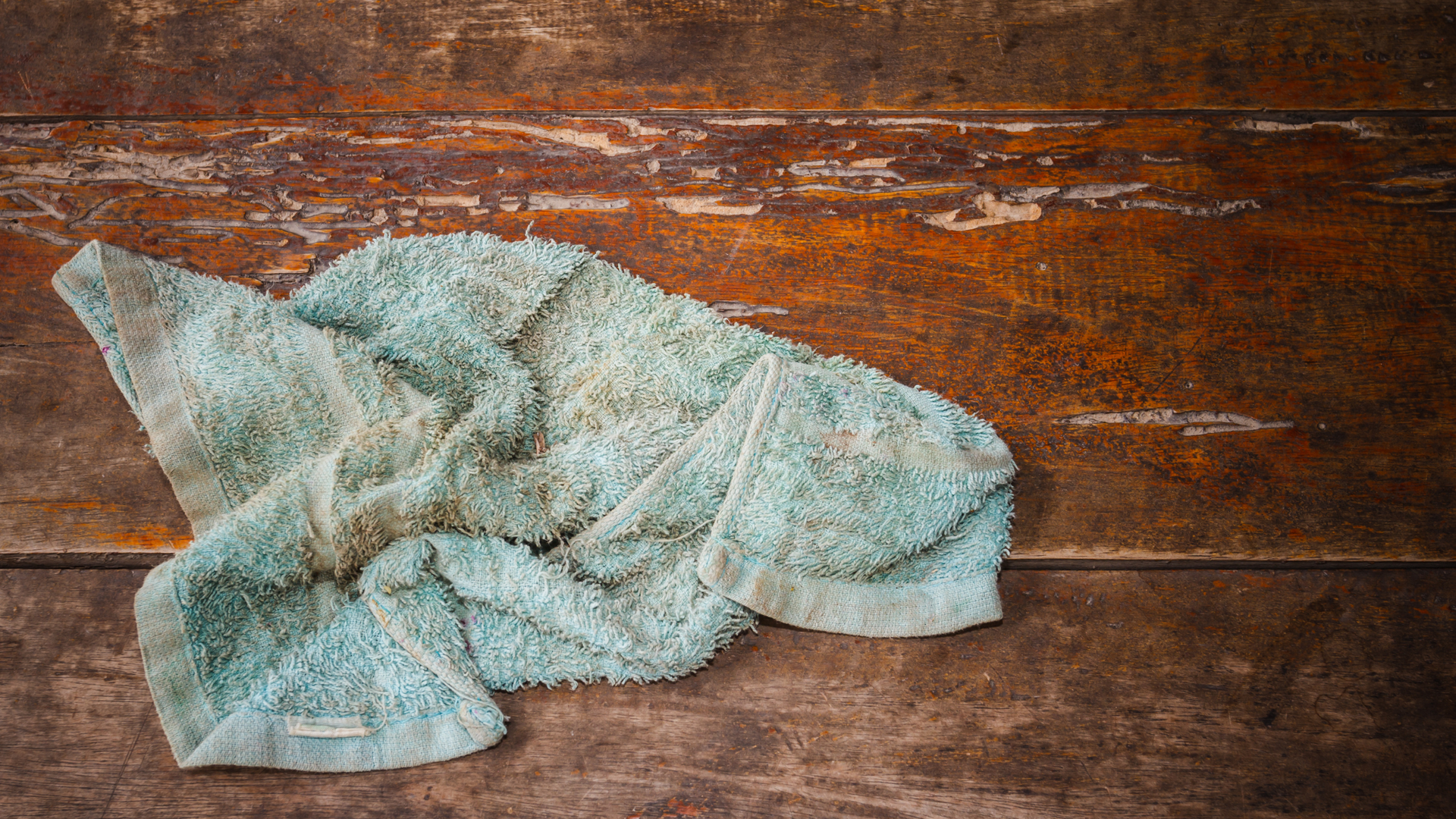 Blue, crumpled towel on a weathered, brown wooden surface.