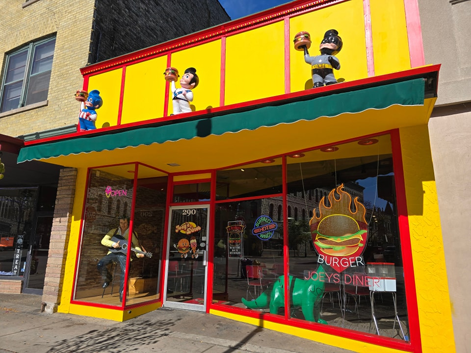 Bright yellow restaurant with cartoon figures on roof; red trim, green awning.