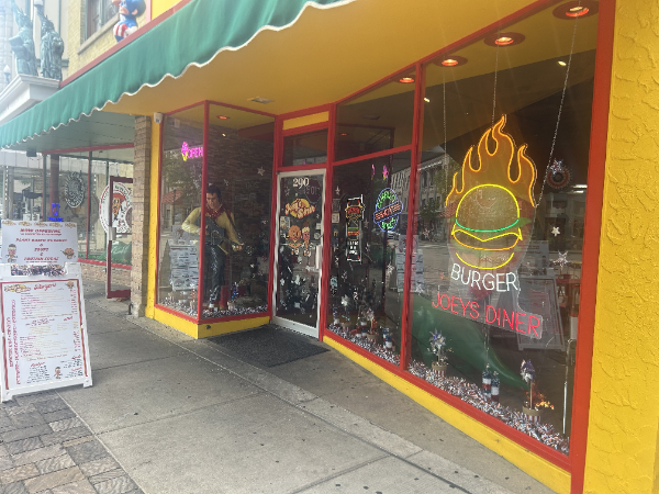 Exterior of Burger Zone restaurant with yellow facade and neon burger sign.