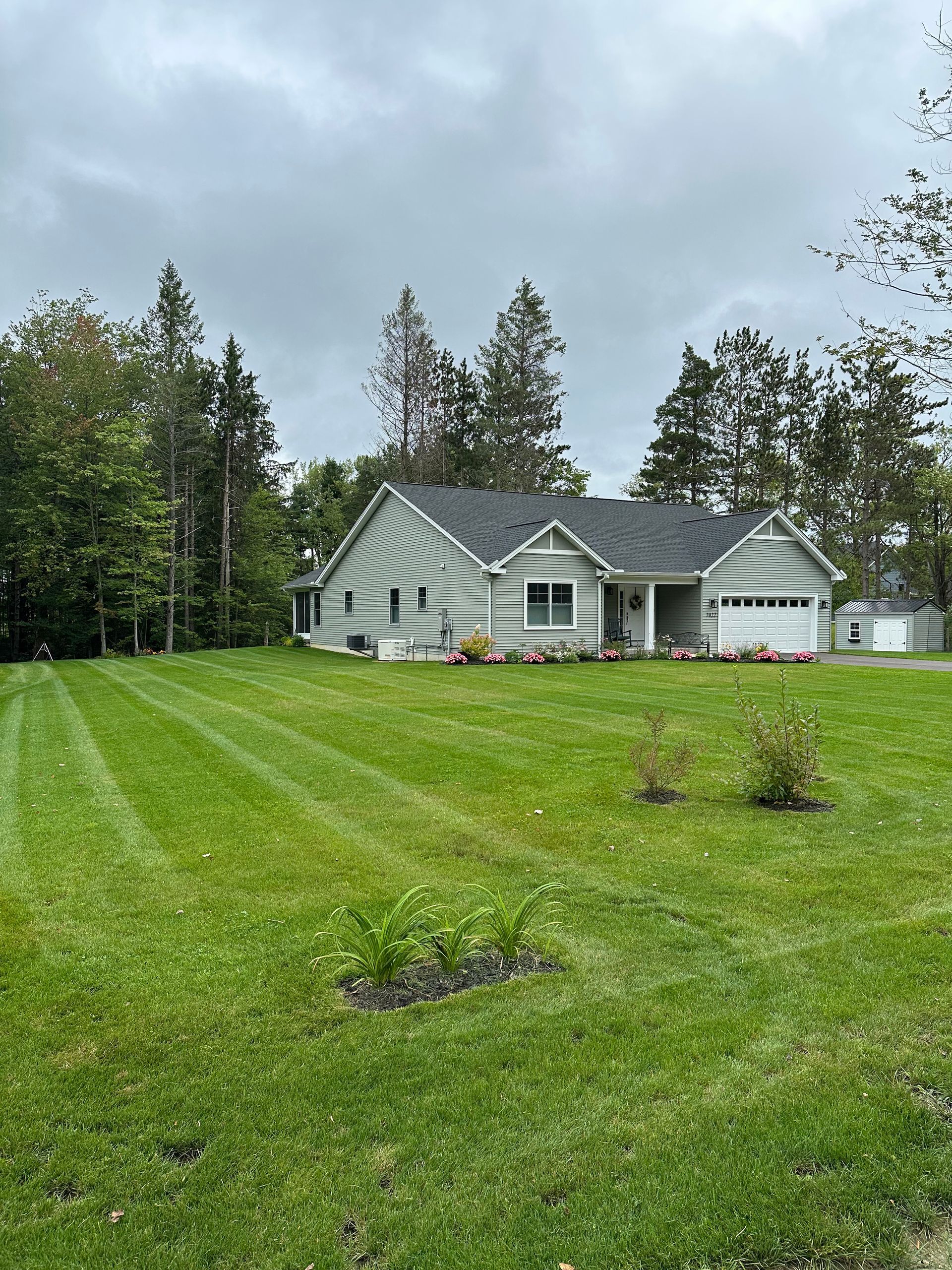 A truck with a snowplow clearing a snow-covered driveway in front of a house.