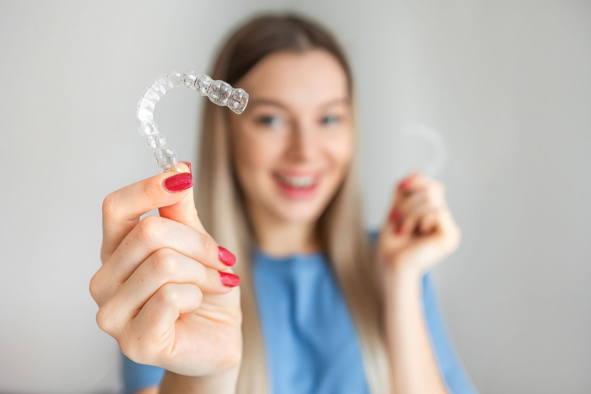 Happy patient smiling while holding Invisalign aligners.
