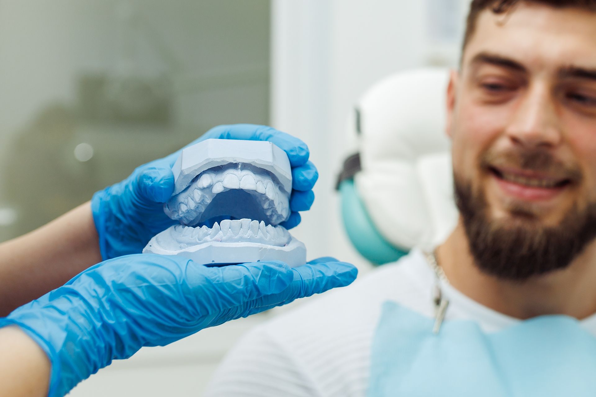 A dentist is holding a model of a man 's teeth.