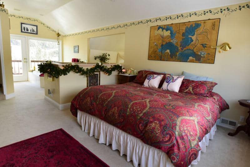 A bedroom with a large bed and a painting on the wall