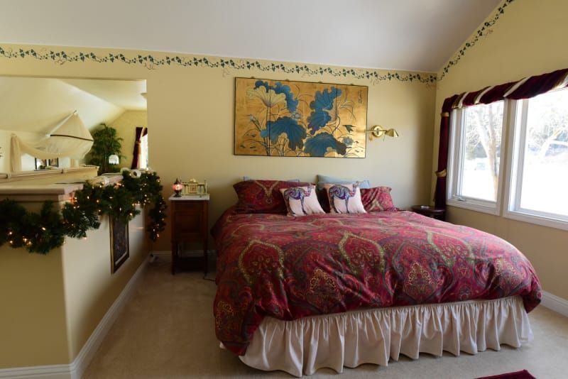 A bedroom with a large bed and a painting on the wall