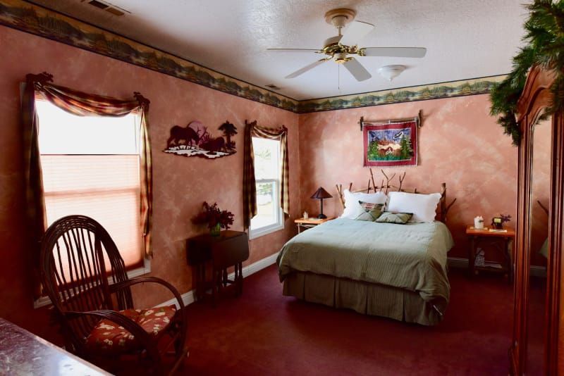 A bedroom with a large bed and a ceiling fan