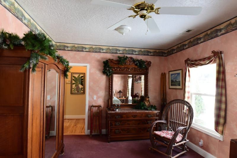 A bedroom with a rocking chair a dresser and a mirror