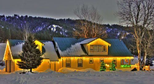 A house is lit up with christmas lights in the snow