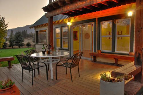 There is a table and chairs on the deck of a house.
