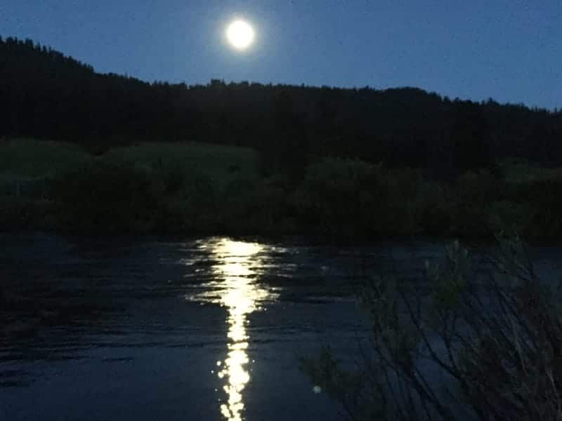 A full moon shines over a river at night
