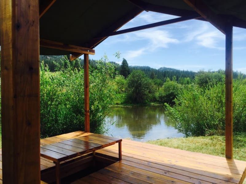 A wooden deck with a table and chairs overlooking a lake.