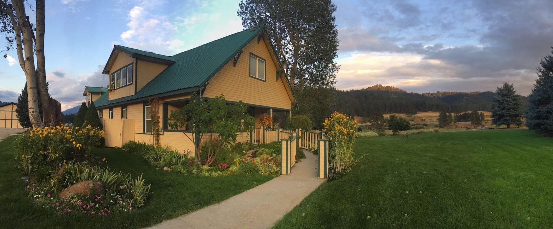 A large house with a green roof is sitting on top of a lush green field.