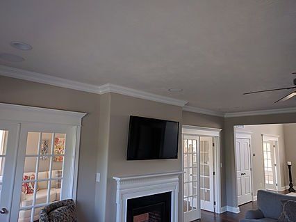 Living room with a fireplace, TV, crown molding, and glass doors.