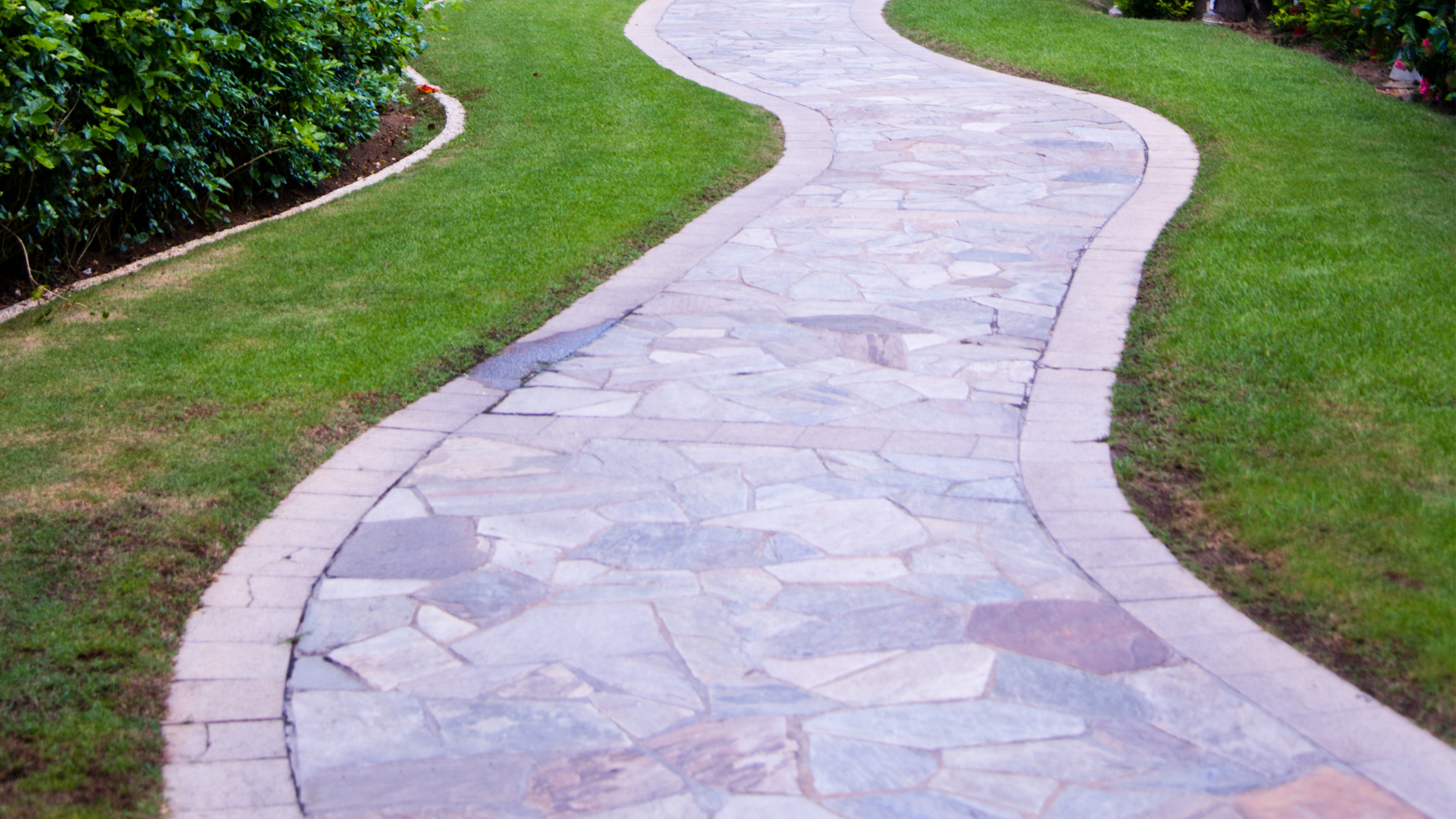 A stone walkway going through a lush green field.