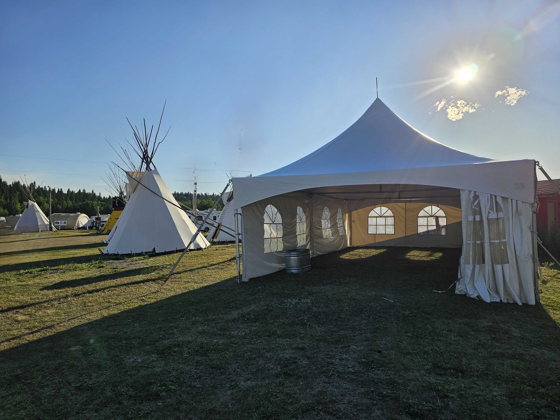 A large white tent is sitting in the middle of a grassy field.