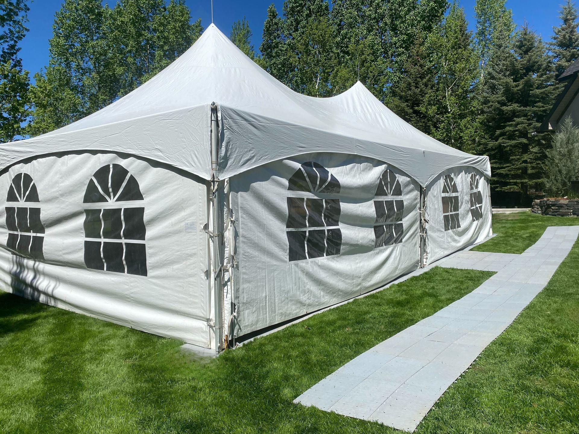 A row of white tents are sitting on top of a lush green field.