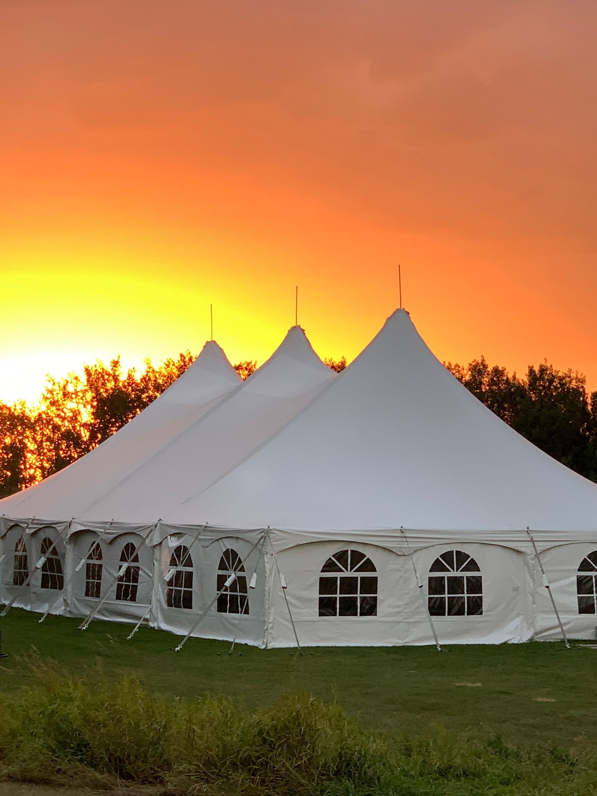 A large white tent with a sunset in the background