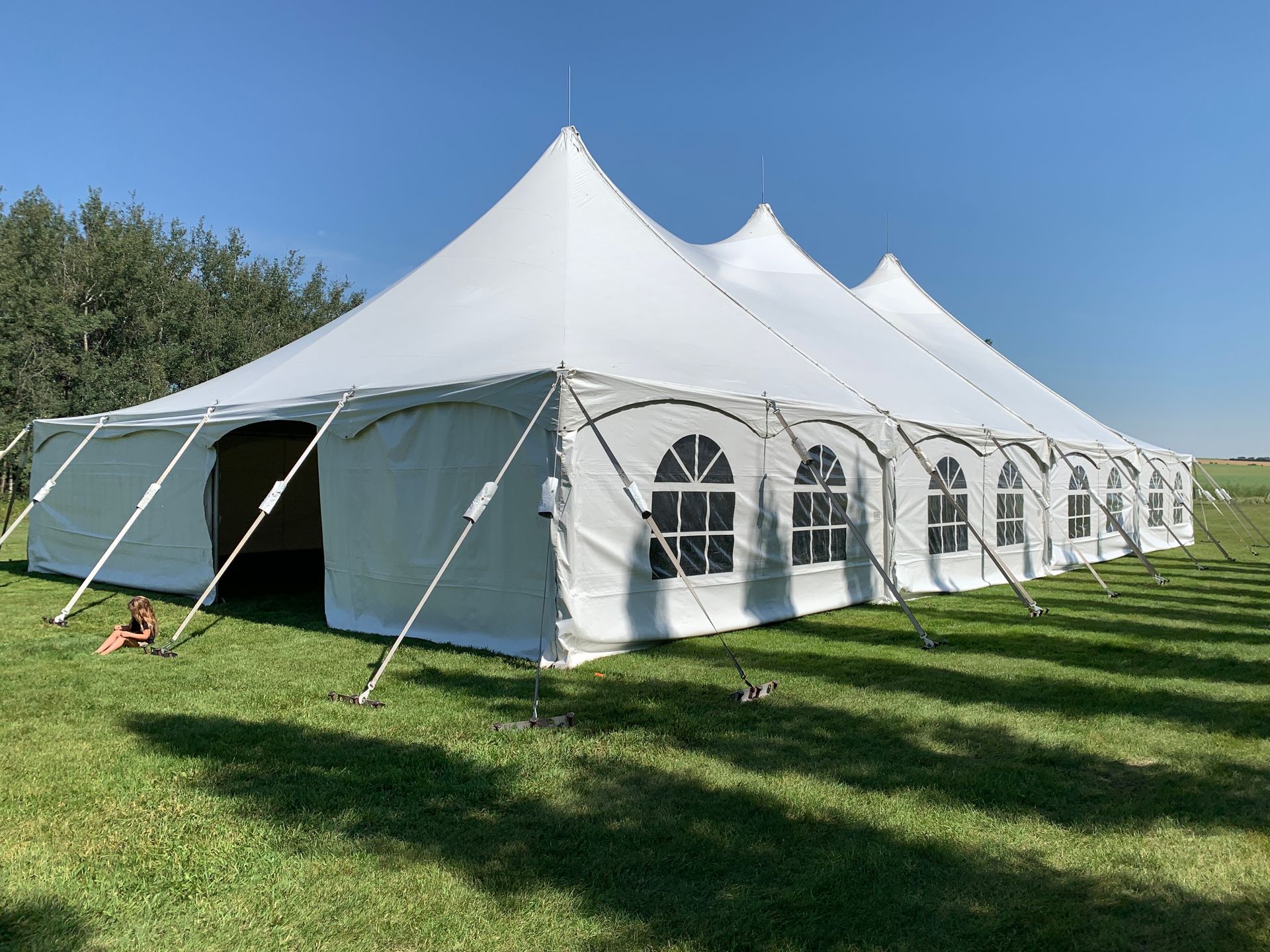 A large white tent is sitting in the middle of a grassy field.