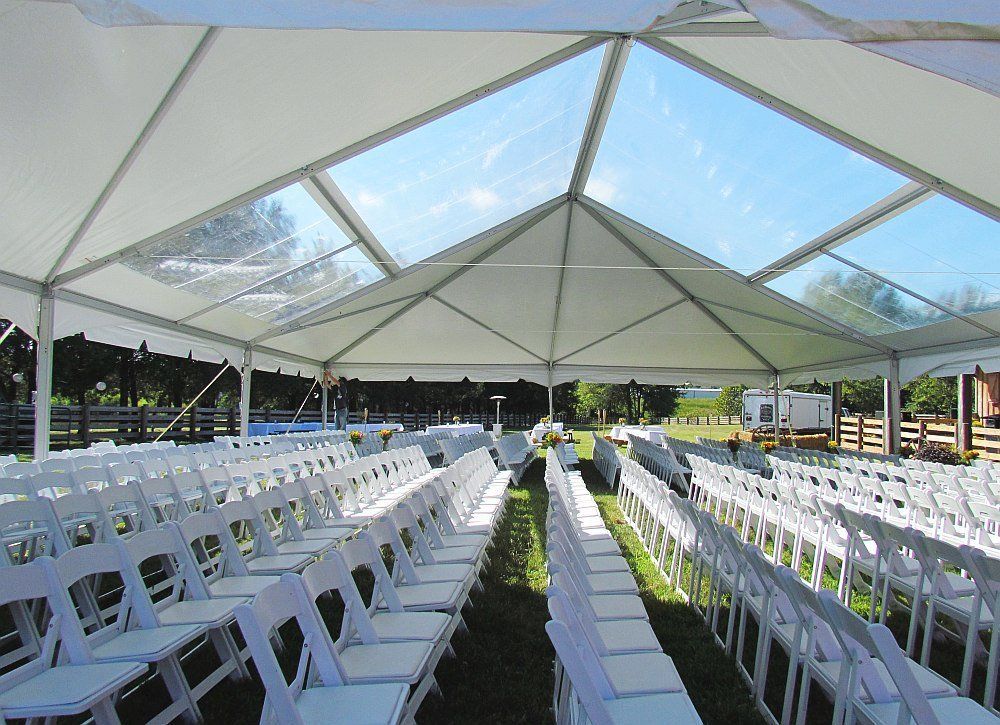 Rows of white folding chairs under a clear tent