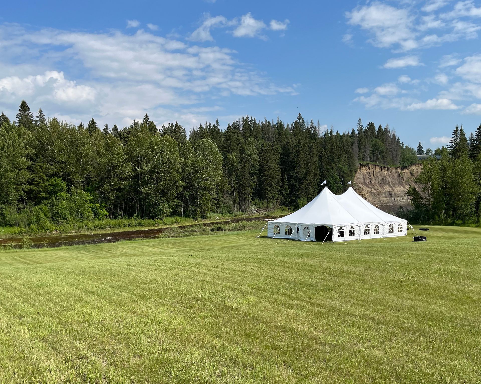 A large white tent is sitting in the middle of a grassy field.