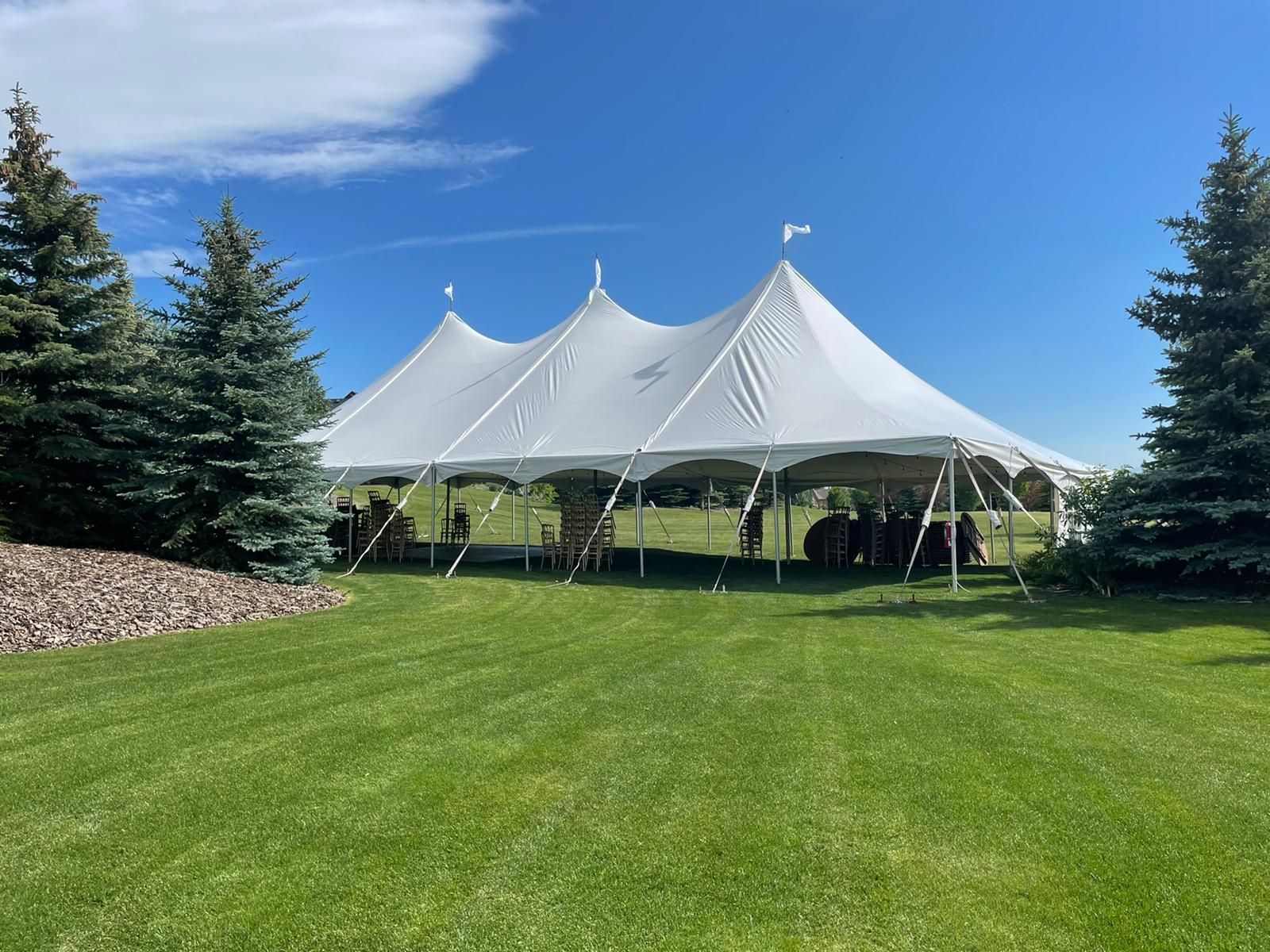 A large white tent is sitting in the middle of a lush green field.