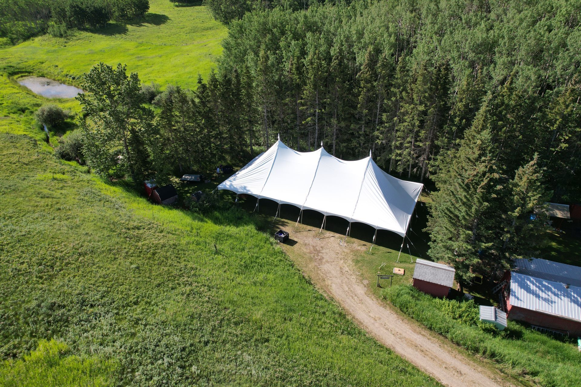 An aerial view of a large tent in the middle of a field surrounded by trees.
