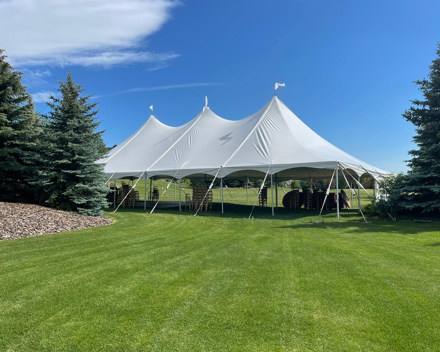 A large white tent is sitting in the middle of a lush green field.