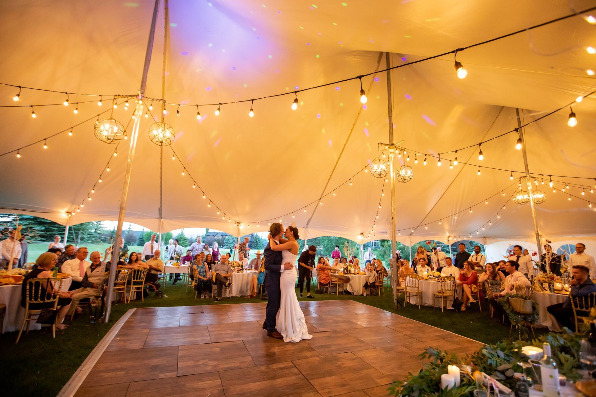 A bride and groom are dancing under a tent at their wedding reception.