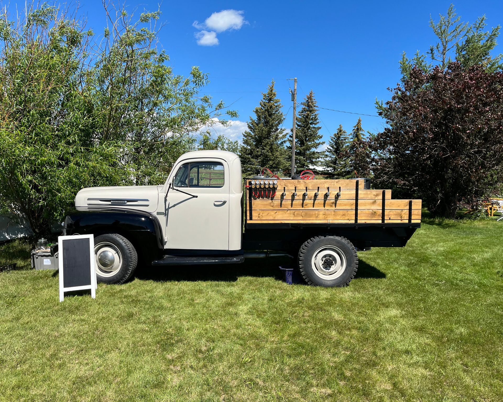 A white truck with a wooden bed is parked in a grassy field.