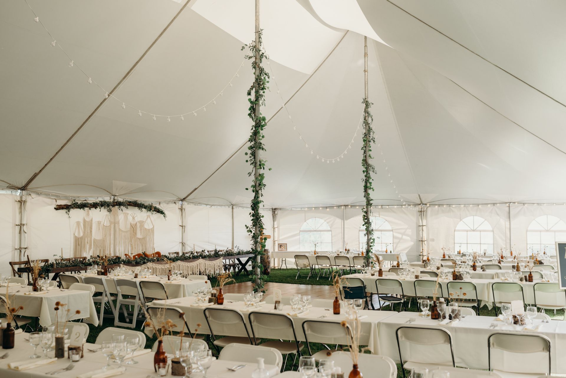 A large tent with tables and chairs set up for a wedding reception.