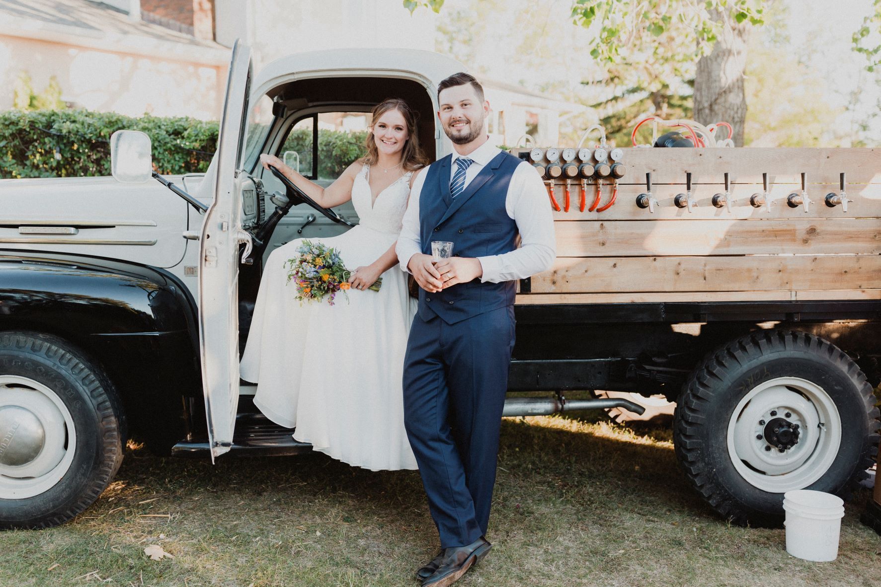 A bride and groom are standing next to a truck.