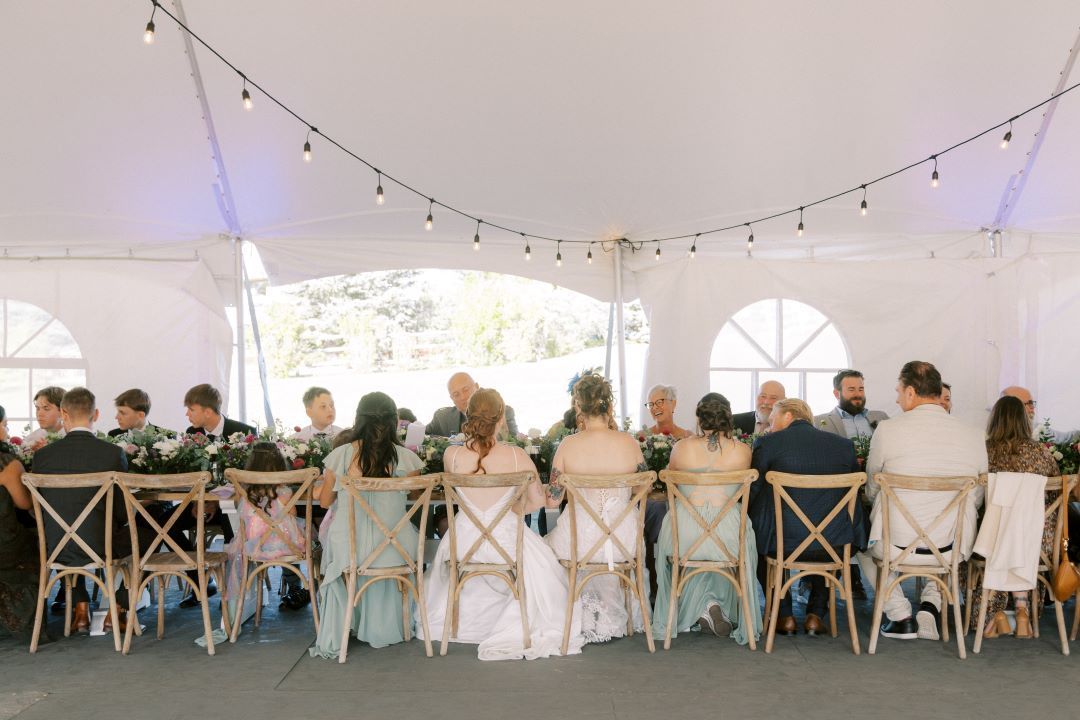 A group of people are sitting at a long table under a tent.