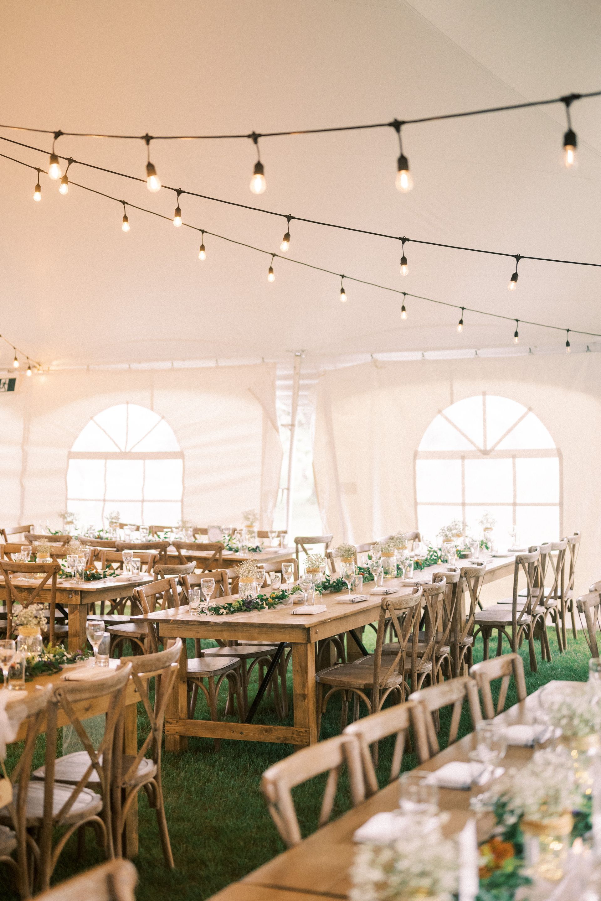 A large tent with tables and chairs set up for a wedding reception.