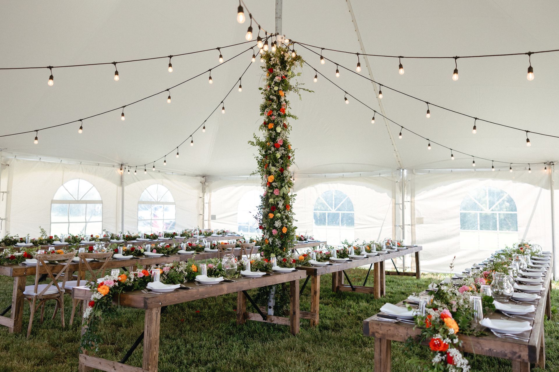 A tent with tables and chairs set up for a wedding reception.