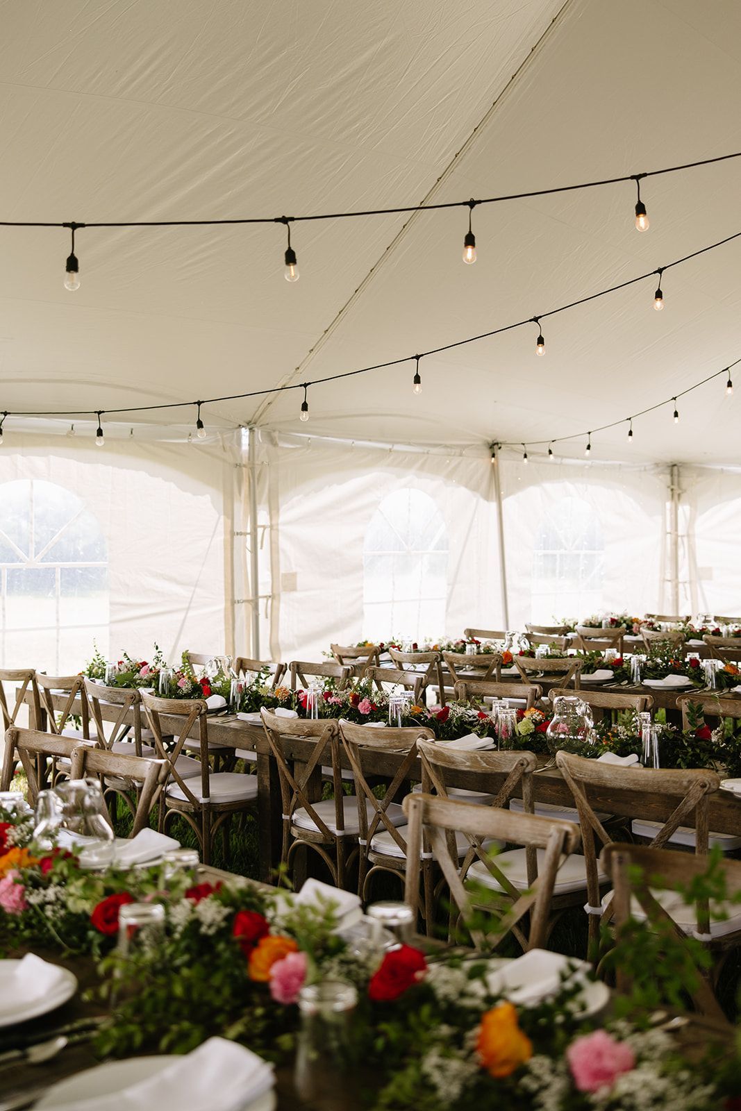 A tent with tables and chairs set up for a wedding reception.