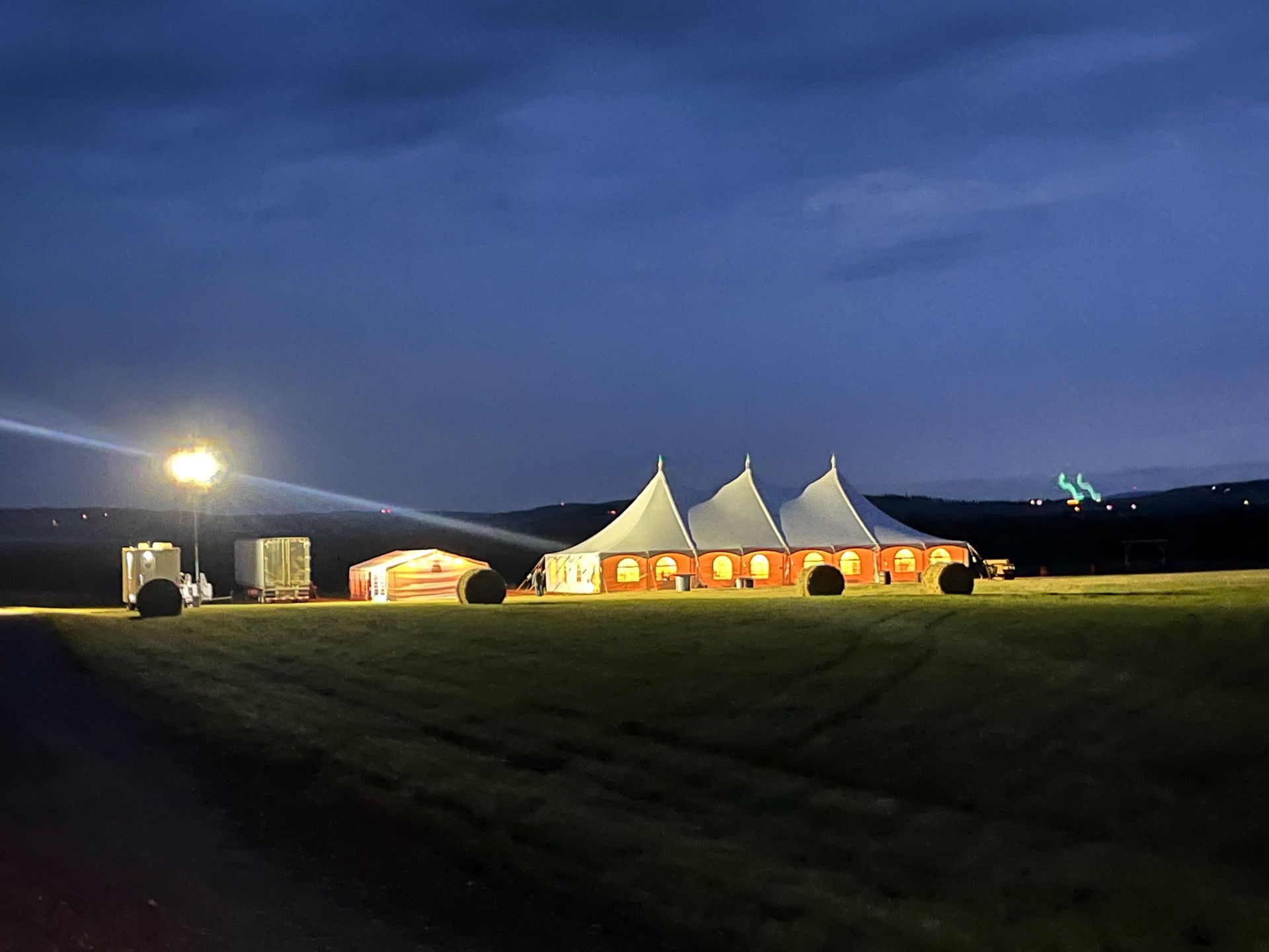 A large tent is lit up in a field at night.