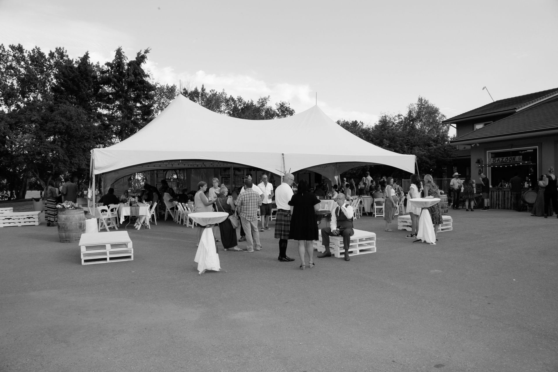 A group of people are standing under a tent in a parking lot.