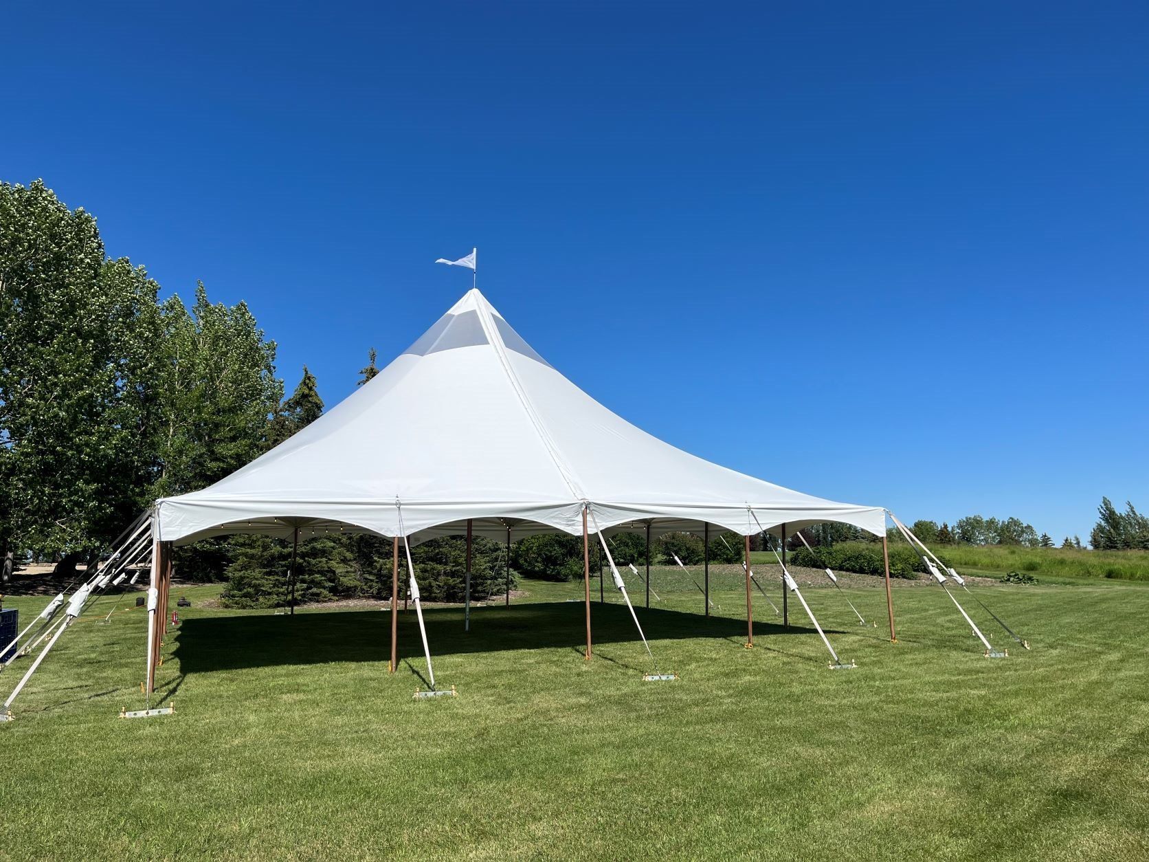 A large white tent is sitting in the middle of a grassy field.