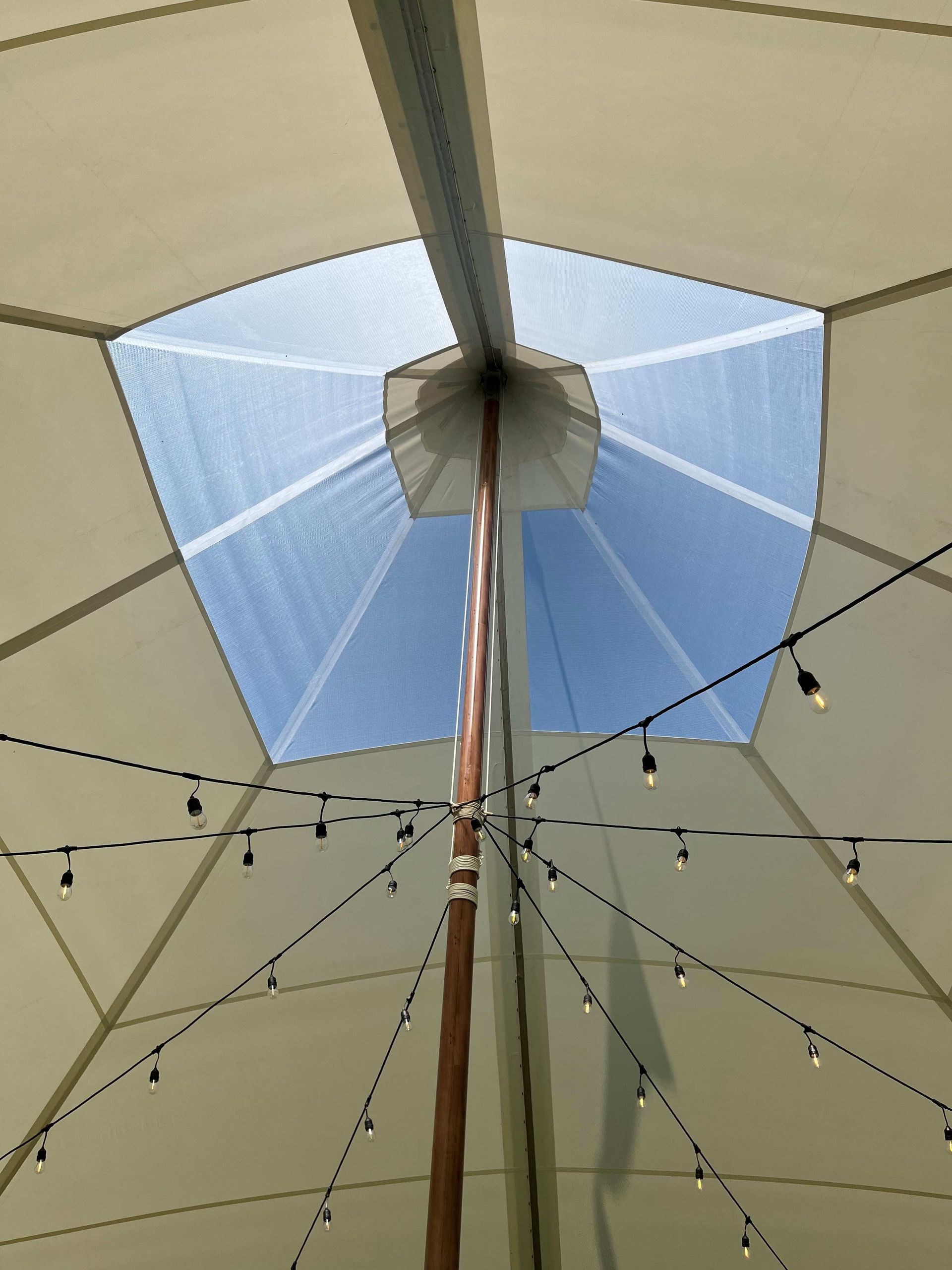 Looking up at the sky through a tent with string lights